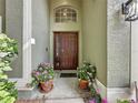 Inviting front entrance with a decorative door, arched window, and colorful potted plants at 2365 Paulette Dr, Haines City, FL 33844