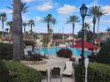 Resort-style pool area with palm trees, comfortable lounge chairs, and vibrant red umbrellas at 247 Verona Ave, Davenport, FL 33897