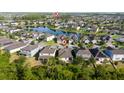 An aerial view showcases a neighborhood with a lake and homes nestled within a backdrop of green trees at 3890 Prairie Reserve Blvd, Orlando, FL 32824
