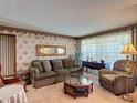 Cozy living room featuring classic wallpaper, plush seating, and natural light at 724 Knob Hill Cir, Kissimmee, FL 34744