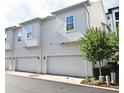 Two-car garages with white doors on a modern townhome, complemented by well-kept landscaping at 932 Wild Date Ln, Lake Mary, FL 32746