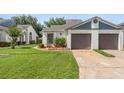 Single-story home features a well-manicured lawn and an attached two-car garage and mature flowering landscaping at 98 Lakepointe Cir, Kissimmee, FL 34743
