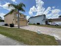 Two-story home with tan exterior, brick paver driveway, plus a palm tree under a blue sky with light, puffy clouds at 1505 Chevington Ct, Orlando, FL 32824