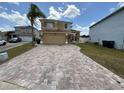 Two-story home with tan exterior and long brick paver driveway under a blue sky with light, puffy clouds at 1505 Chevington Ct, Orlando, FL 32824