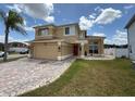 Two-story home with tan exterior, brick paver driveway and entry way, plus a red door under a blue sky at 1505 Chevington Ct, Orlando, FL 32824