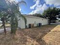 Side exterior view of the house featuring a well-maintained lawn and an air conditioning unit at 15408 Groose Point Ln, Clermont, FL 34714