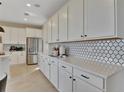Spacious kitchen featuring white cabinetry, stainless steel appliances, quartz countertops, and decorative tile backsplash at 183 Flag Lilly Ln, Umatilla, FL 32784