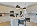 Stylish kitchen boasts white cabinets, a center island with seating, stainless steel appliances, and pendant lighting at 183 Flag Lilly Ln, Umatilla, FL 32784
