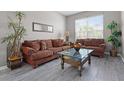 Cozy living room with hardwood-style flooring, couches, plants and large windows for natural light at 209 Rosso Dr, Davenport, FL 33837