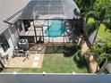 Aerial view of the screened pool, a patio, and a yard with grass and rocks at 2888 Spring Breeze Way, Kissimmee, FL 34744