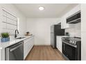 Modern kitchen featuring sleek countertops, stainless steel appliances, white cabinetry, and wood-look floors at 620 Plum Ln, Altamonte Springs, FL 32701