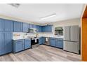 A kitchen featuring blue cabinets, modern stainless steel appliances, a light backsplash, and stylish flooring at 710 California Ave, St Cloud, FL 34769