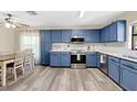 An eat-in kitchen featuring matching blue cabinets, stainless steel appliances, and a ceiling fan with a light at 710 California Ave, St Cloud, FL 34769