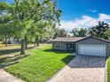 Charming single-Gathering home featuring a brick driveway, well-manicured lawn, and an attached two-car garage at 7823 Bell Blvd, Orlando, FL 32810