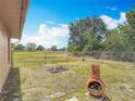 A spacious backyard featuring a fire pit, a rustic terracotta decoration, and a chain-link fence at 923 Gascony Ct, Kissimmee, FL 34759