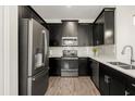 Modern kitchen featuring stainless steel appliances, dark cabinetry, white countertops, and wood-look floors at 11120 Whistling Pine Way, Orlando, FL 32832