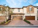 Townhome exterior showcasing brick and stucco facade, complemented by a paver driveway and well-maintained landscaping at 1231 Sandwedge St, Davenport, FL 33896