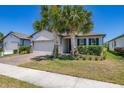 Attractive single-story home with a brick driveway, two-car garage, and beautiful palm trees at 17324 Bracken Fern Ln, Clermont, FL 34714