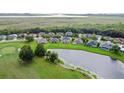 Aerial view showcases homes nestled around a pond and golf course, surrounded by lush greenery at 1976 The Oaks Blvd, Kissimmee, FL 34746