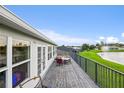 Back deck with railing overlooking pond, with an outdoor dining table and chairs at 1976 The Oaks Blvd, Kissimmee, FL 34746