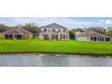 Backyard of home featuring deck, patio, and lush green lawn extending to a serene pond at 1976 The Oaks Blvd, Kissimmee, FL 34746