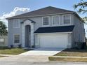 Well-maintained two-story home featuring light gray stucco, white trim, black roof, and a spacious driveway at 1976 The Oaks Blvd, Kissimmee, FL 34746