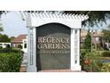 Community sign for Regency Gardens Condominiums with lush landscaping and mature trees at 4301 Lizshire Ln # 306, Orlando, FL 32822