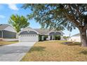 Home featuring an attached two car garage, mature trees and a front yard swing set at 5512 Hamlin Close, Davenport, FL 33896