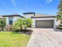 Beautiful home featuring a well-manicured lawn, tropical landscaping, a paver driveway, and a spacious two-car garage at 684 San Augusto Dr, Poinciana, FL 34759
