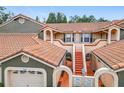 Inviting two-story townhome showcasing a red tile roof, stucco facade, and pedestrian access to upper units at 7806 Sugar Brook Ct # 7806, Orlando, FL 32819