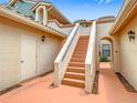 Exterior stairway leading to townhome, featuring stucco walls and a terra cotta tiled landing at 7806 Sugar Brook Ct # 7806, Orlando, FL 32819