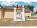 Charming tan home featuring a columned entry way, a well-maintained lawn, and a beautiful blue sky at 115 Anzio Dr, Kissimmee, FL 34758