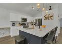 Modern kitchen with white cabinets, stainless steel appliances, quartz countertops, and stylish pendant lighting at 147 Bridgewater Dr, Davenport, FL 33897