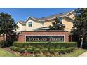Well-maintained Woodland Terrace community sign with colorful landscaping and beautiful townhomes in the background at 15851 Woodland Spring Ct, Orlando, FL 32828