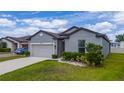 Beautiful single-Gathering home showcasing well-maintained landscaping, a two-car garage, and a welcoming front entrance at 1821 Cayman Cove St., St Cloud, FL 34772