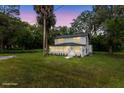 A nighttime view of the home highlighting the exterior features including the yard and the front entryway at 5851 Se Drew Rd, Belleview, FL 34420