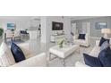 Bright, open-concept living room with stylish white furniture, modern decor, and a seamless flow to the kitchen at 5851 Se Drew Rd, Belleview, FL 34420