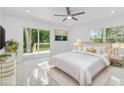 A bright main bedroom featuring stylish decor, a modern ceiling fan, and a sliding glass door to the deck at 5851 Se Drew Rd, Belleview, FL 34420