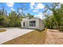 Newly renovated one-story home featuring a white exterior, minimalist design, concrete driveway, and natural setting at 610 E Euclid Ave, Deland, FL 32724