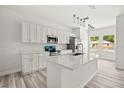 Modern kitchen with white cabinets, quartz countertops, an island, stainless steel appliances, and stylish pendant lighting at 610 E Euclid Ave, Deland, FL 32724