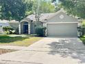 Single-story home with a two car garage and gray painted facade at 671 Carey Way, Orlando, FL 32825
