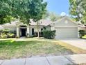Charming single-story home featuring a well-maintained lawn, mature trees and a two car garage, showcasing curb appeal at 671 Carey Way, Orlando, FL 32825