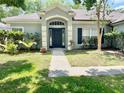 Inviting single-Gathering home with neutral exterior paint, arched entry and well-manicured front lawn, exemplifying suburban charm at 671 Carey Way, Orlando, FL 32825