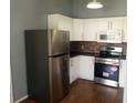 Modern kitchen with stainless steel appliances, white cabinets, and stone backsplash at 8750 Se 88Th Ave, Ocala, FL 34472