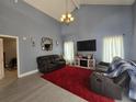 Spacious living room with high ceilings, gray walls, wood floors, and comfortable seating around a TV at 101 Grand Junction Blvd, Orlando, FL 32835