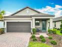Charming home featuring a brick driveway, a two-car garage, and a cozy front porch seating area at 1029 Umbria Dr, Poinciana, FL 34759