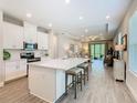 Open-concept kitchen flowing into the living area, featuring white cabinets, a large island, and stainless steel appliances at 1029 Umbria Dr, Poinciana, FL 34759