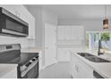 Modern kitchen featuring white cabinets, stainless steel appliances, and a stylish black sink faucet at 1251 Ash Tree Cv, Casselberry, FL 32707