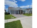 Charming single-story home with a well-manicured lawn, gray garage doors, and a beautiful stone facade at 19235 Allium Pl, Orlando, FL 32827