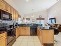 Kitchen with granite countertops, oak cabinetry, black appliances, and an island for additional counter space at 207 Bailey Cir, Davenport, FL 33897